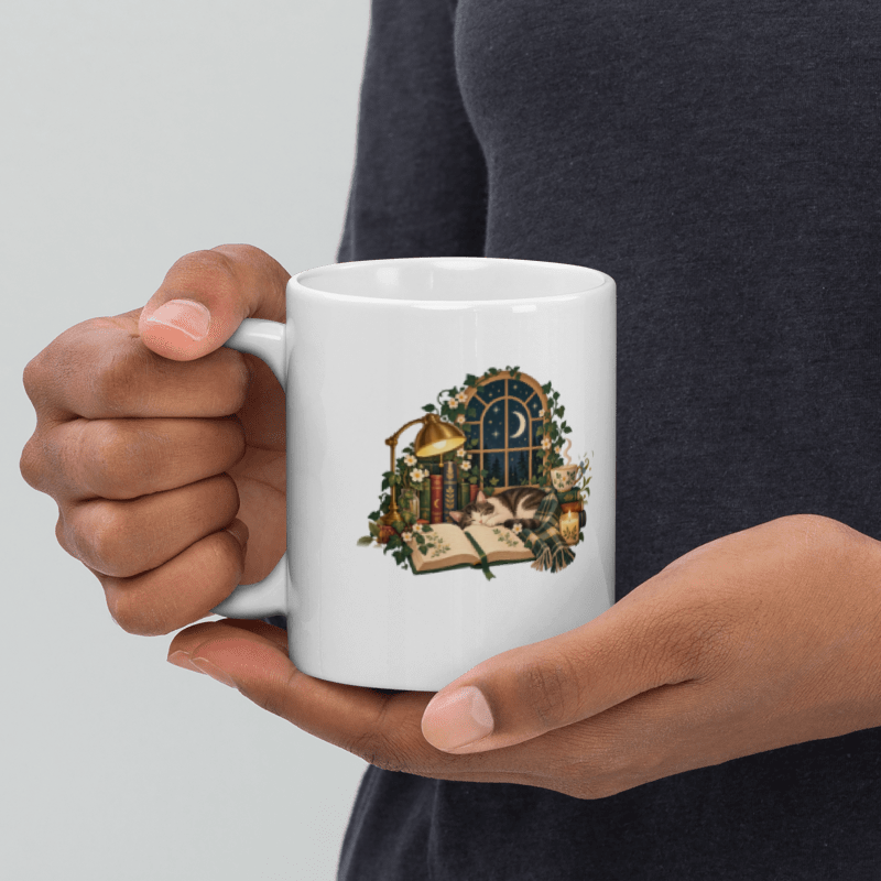 hand holding a white Midnight Reading Club mug with the moonlit illustration facing out