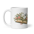 white glossy 11 oz ceramic mug with the Where Stories Bloom open book, roses and butterfly illustration, handle on the left