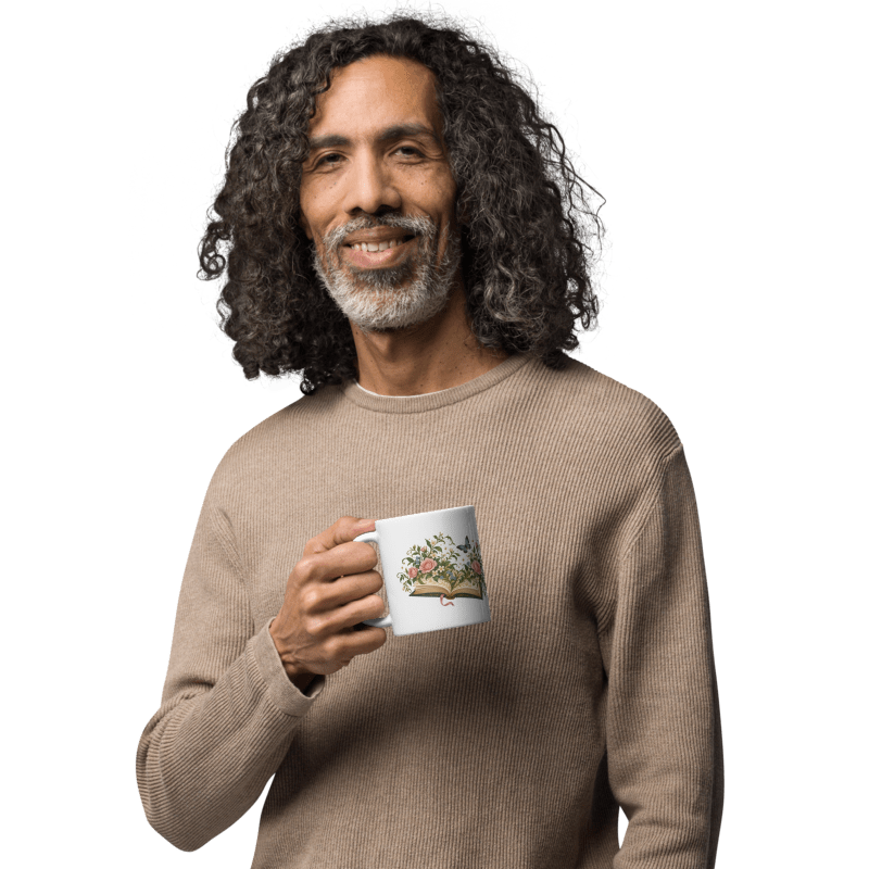 man in a beige sweater holding a white Where Stories Bloom mug with the floral illustration facing out